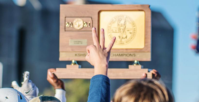 A Mill Valley fan holds up three fingers during the team's celebration of their third straight state championship Saturday in Pittsburg. (Photo by Lori Wood Habiger) A Mill Valley fan holds up three fingers during the team's celebration of their third straight state championship Saturday in Pittsburg. (Photo by Lori Wood Habiger)